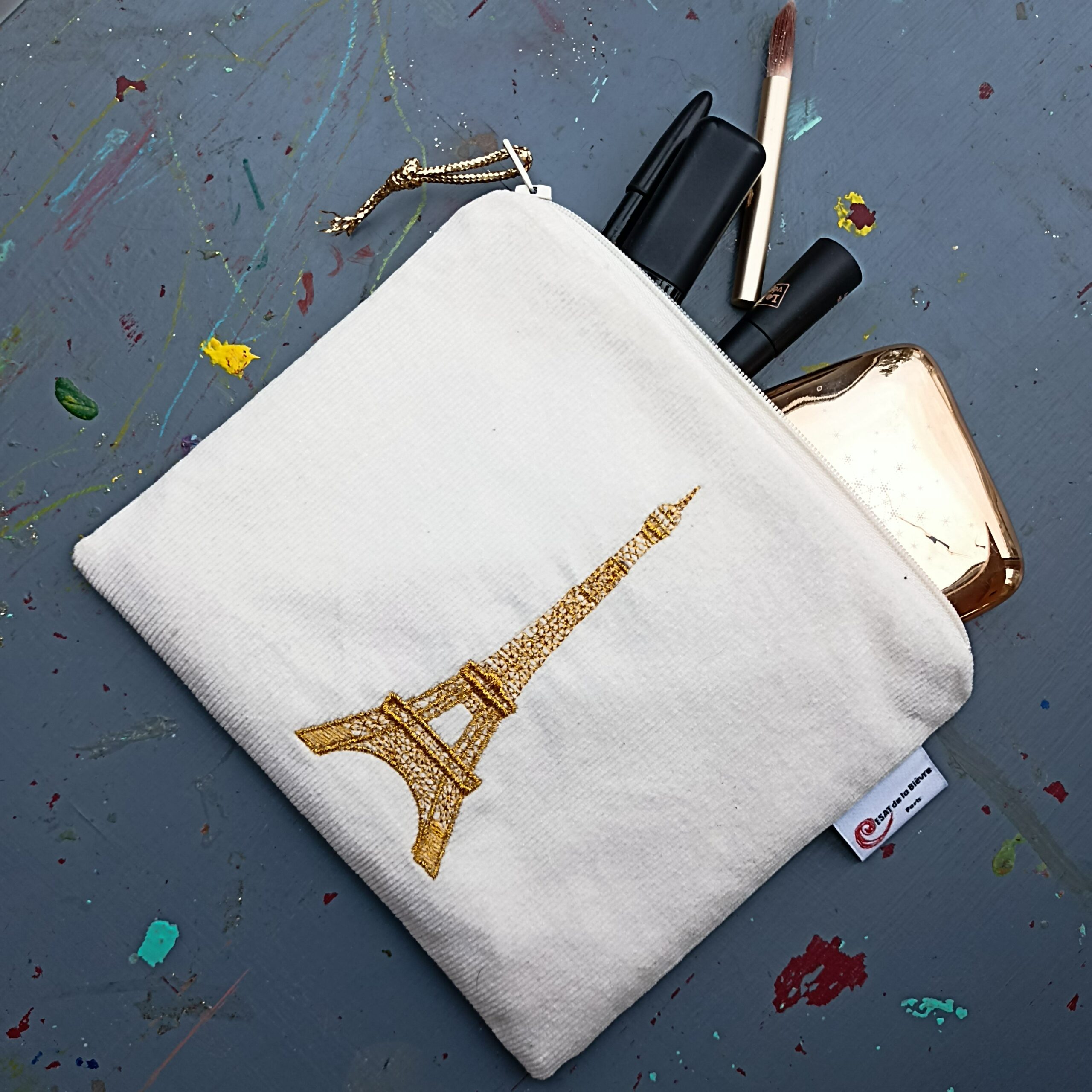 Pochette « Tour Eiffel » – Broderie artisanale de l’ESAT de la Bièvre Pochette brodée « Tour Eiffel » en coton et simili-cuir, création de l’ESAT de la Bièvre.